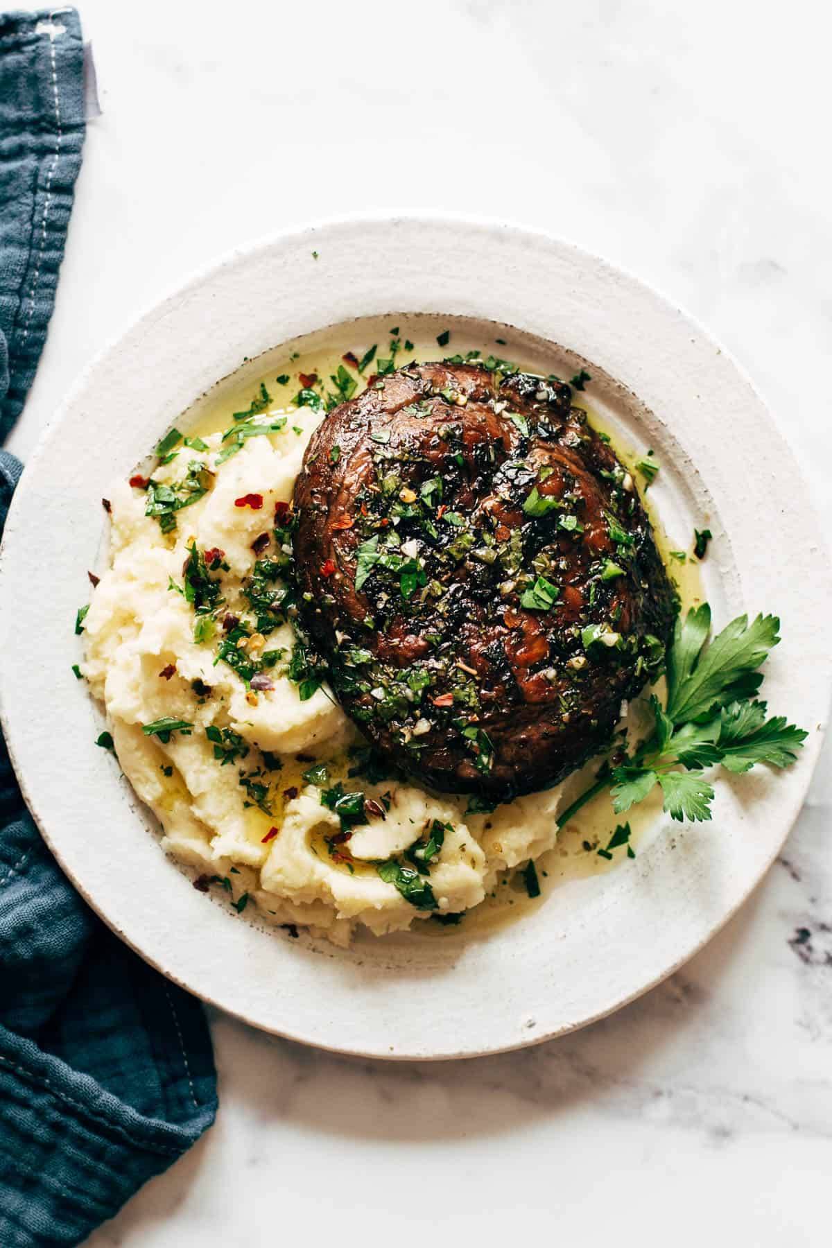 Grilled portable mushroom on a bed of mashed potatoes with lots of herbs.
