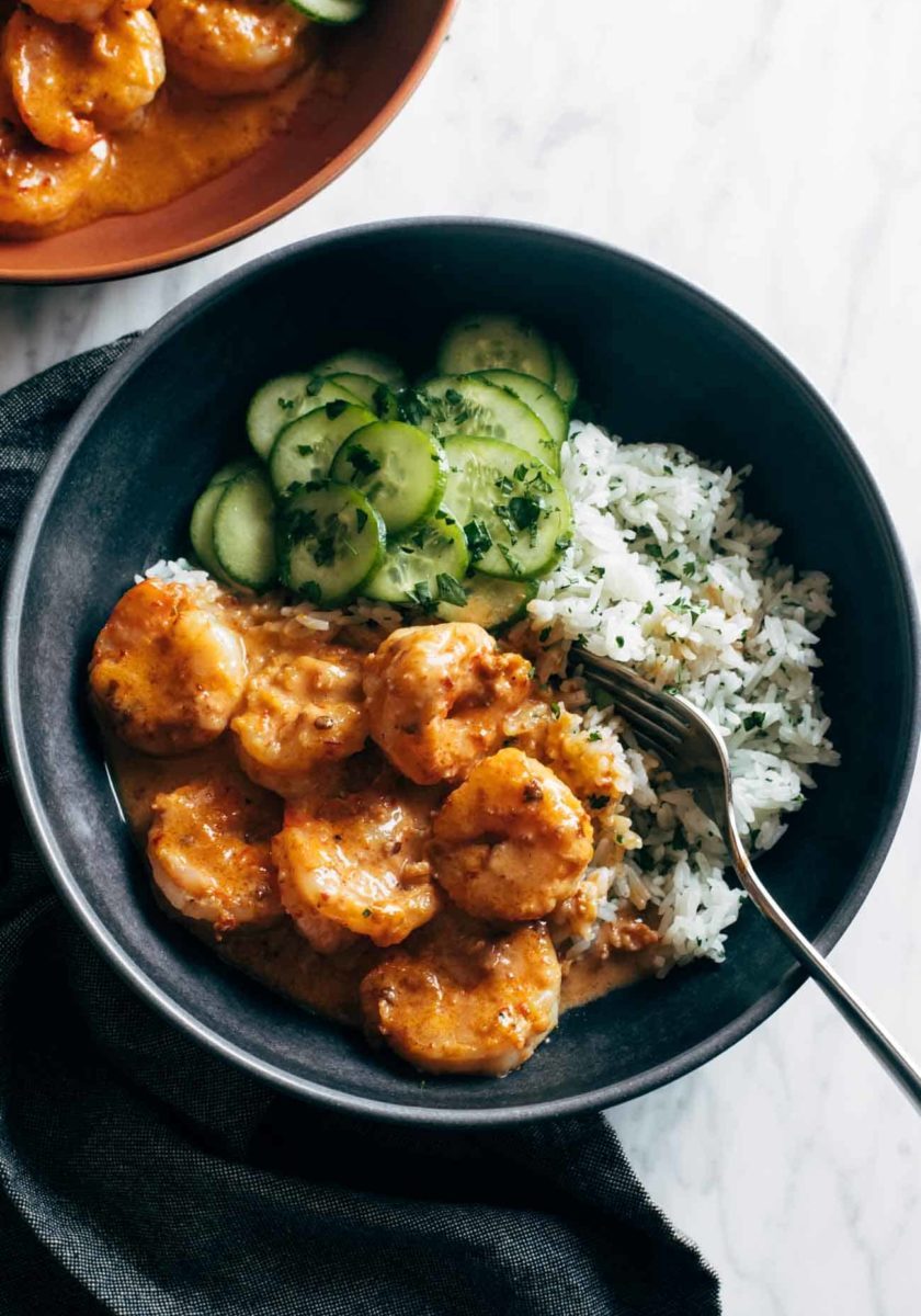 A bowl of shrimp and greens with some rice.