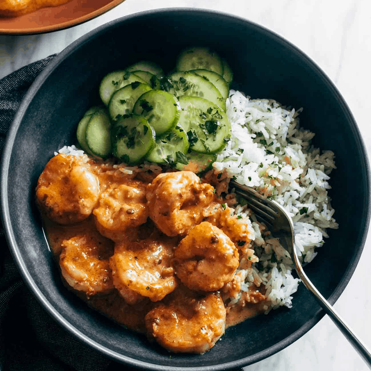 Chipotle orange shrimp in a bowl with cucumbers and cilantro rice.