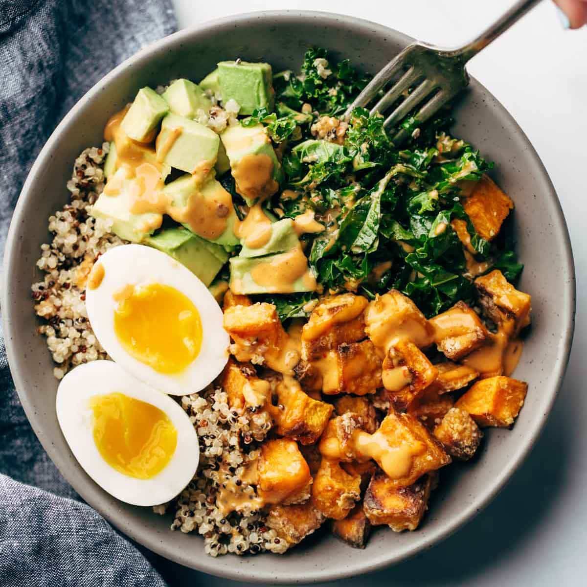 A chipotle tahini bowl with roasted sweet potato, fresh avocado, kale, quinoa and a soft boiled egg.