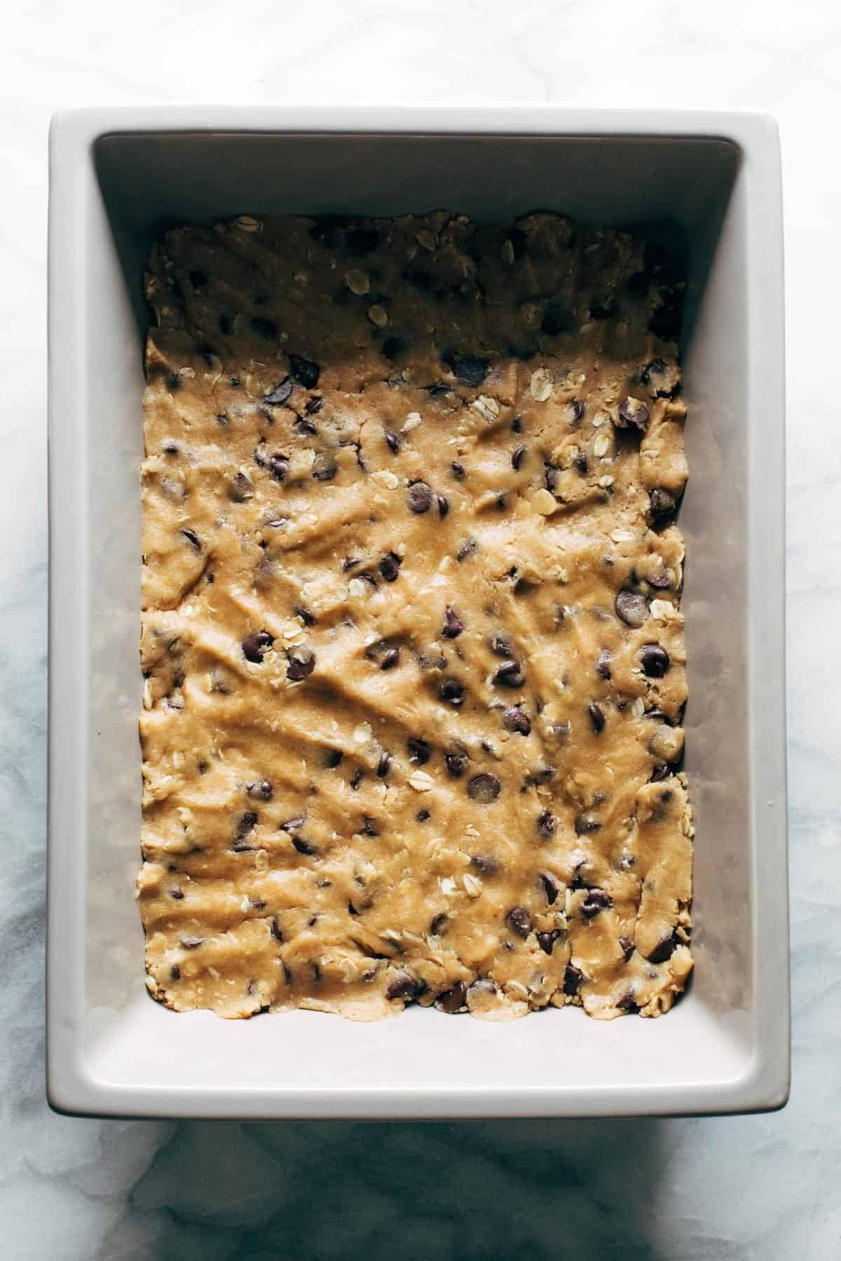 Chocolate chip cookie dough pressed in a pan.