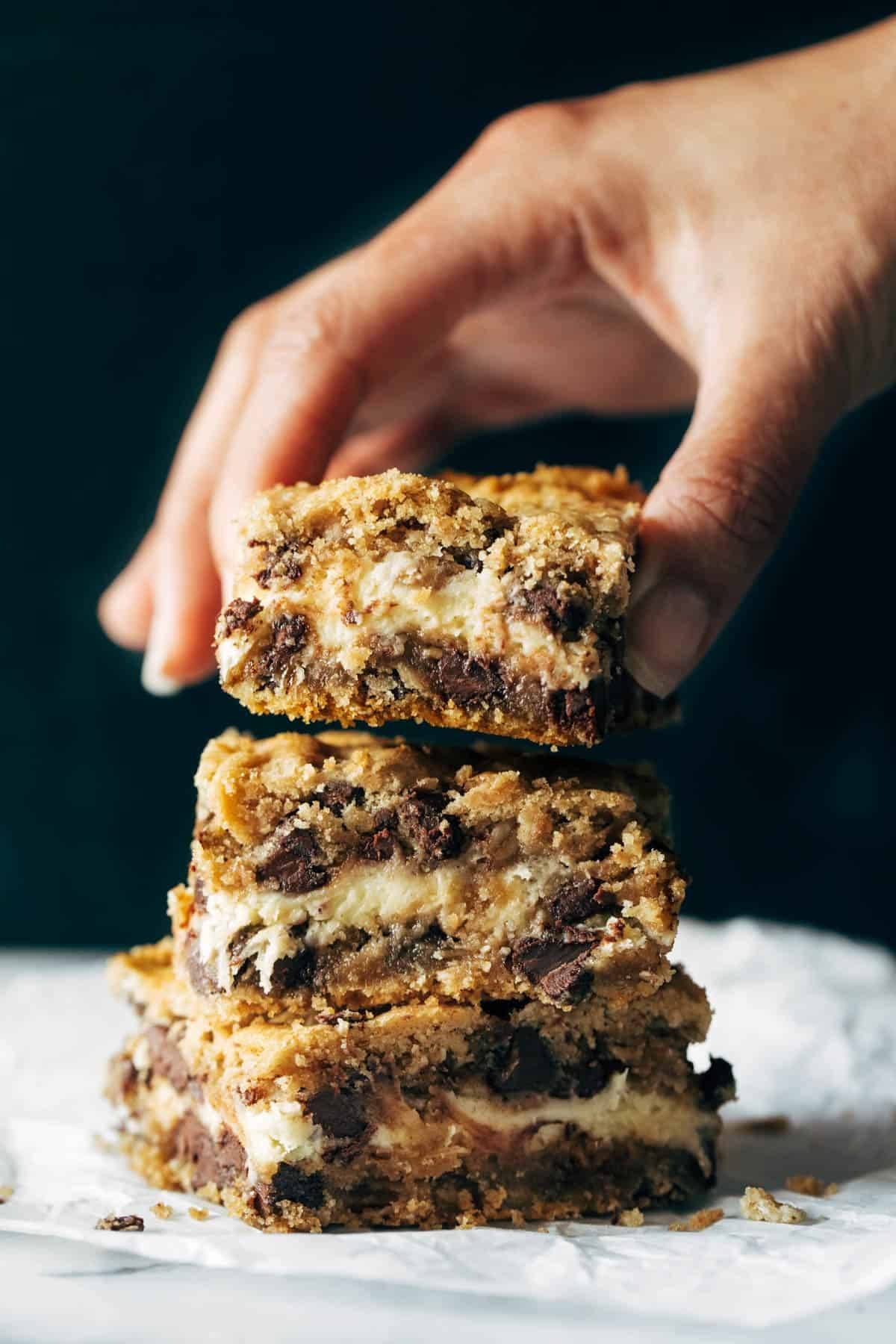 Peanut Butter Chocolate Chip Cookie Cheesecake Bars stacked on top of eachother.