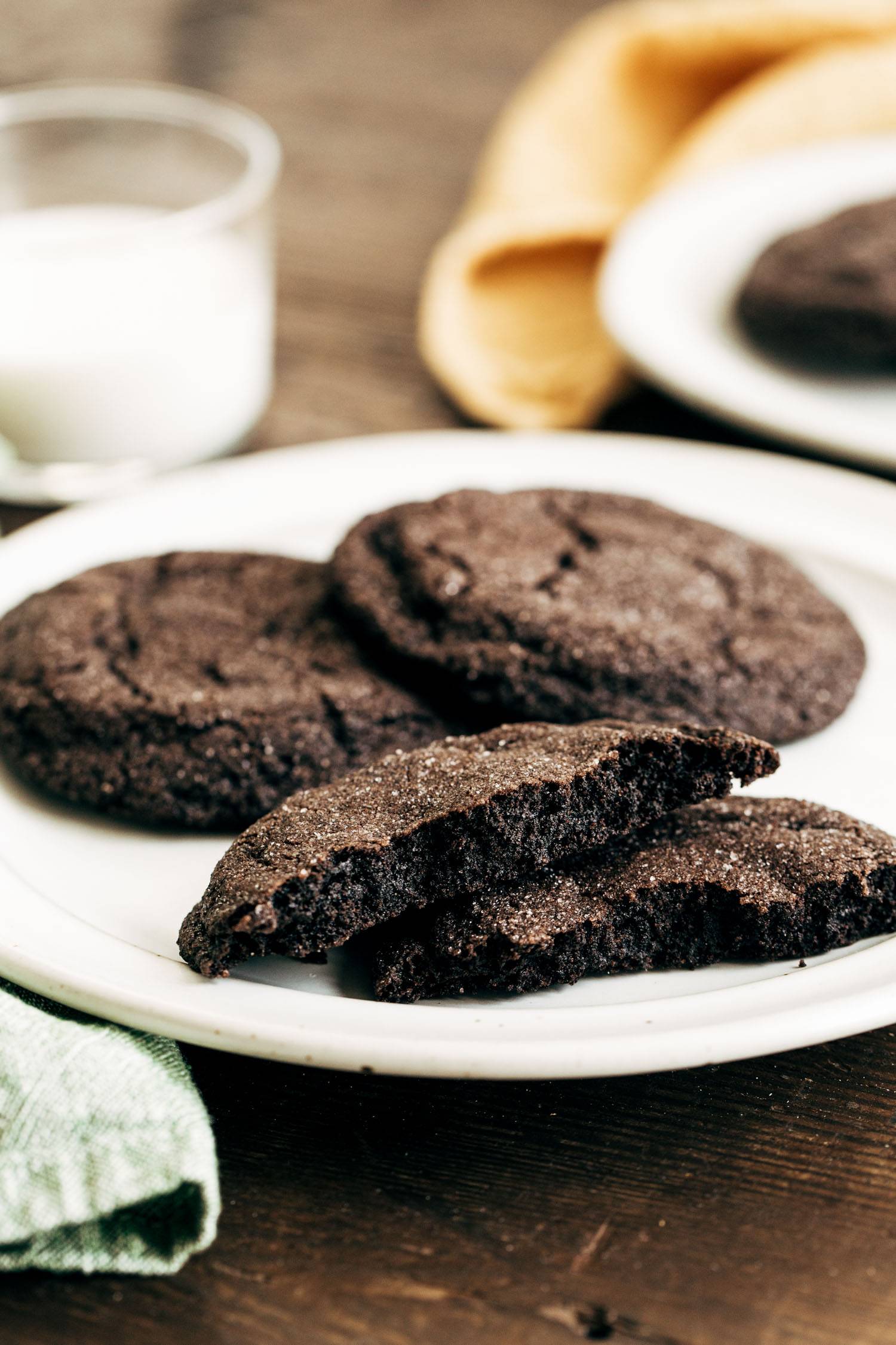Dark chocolate cookies on a plate with a bite taken out of them.