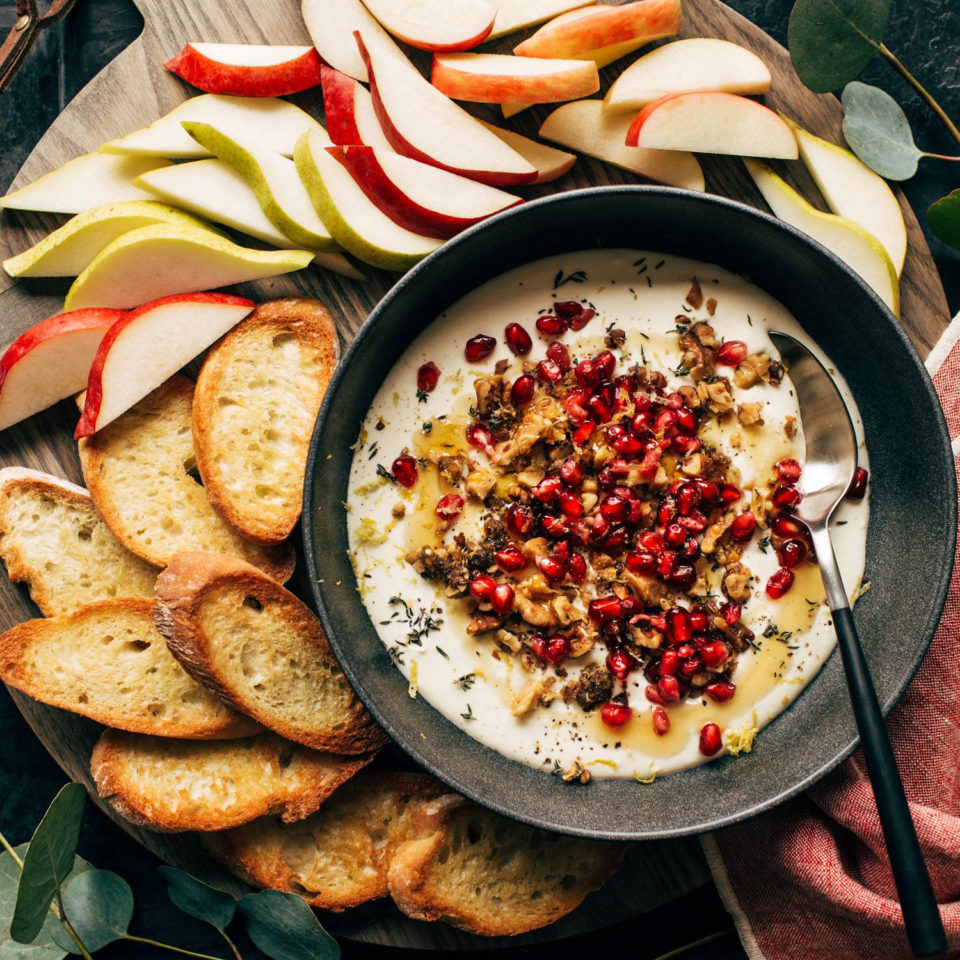 Whipped feta in a bowl with crackers and fruit on the side.