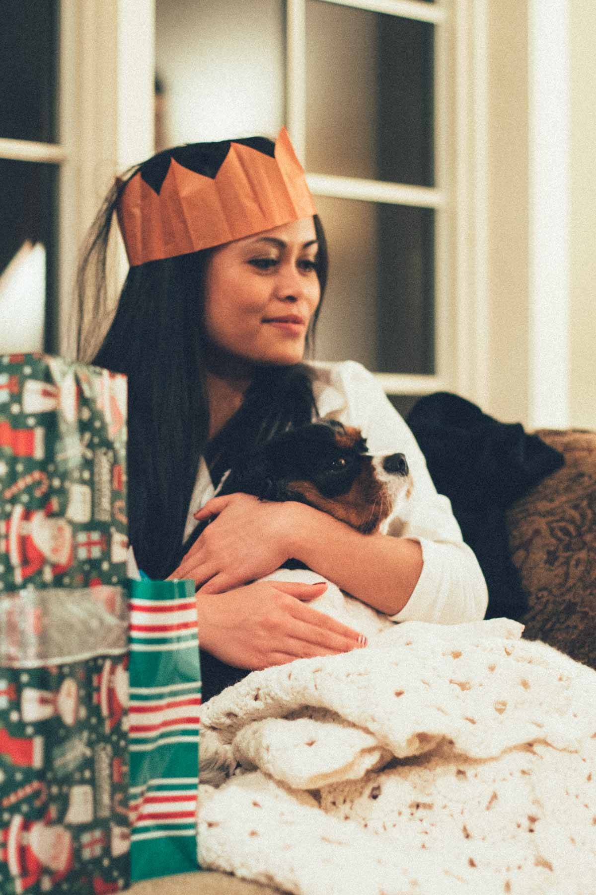 Girl wearing a paper crown holding a dog.