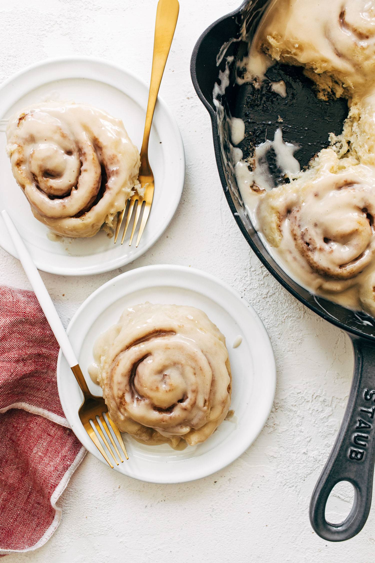 Cinnamon rolls with glaze on plates with forks.