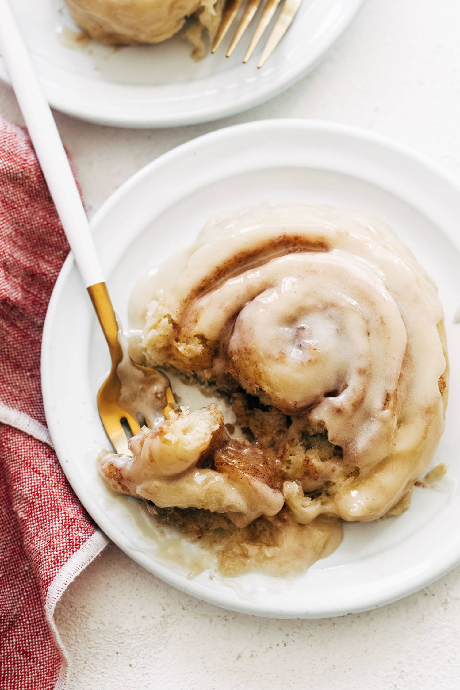 Cinnamon roll with glaze on a plate with a fork.