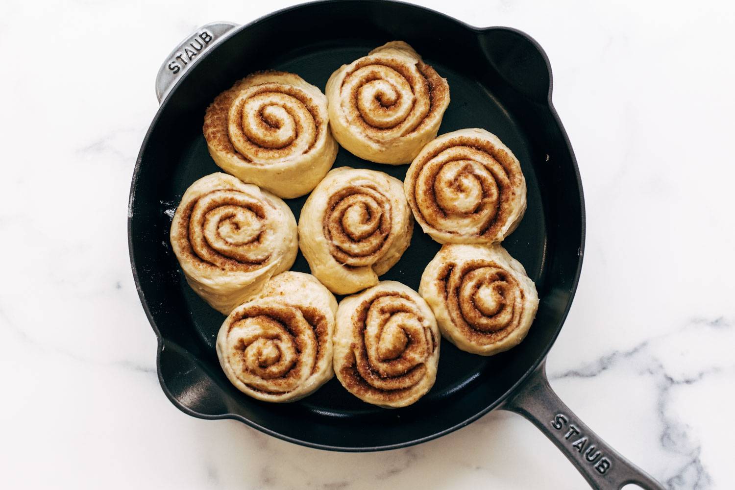 Unbaked cinnamon rolls in a cast iron skillet.
