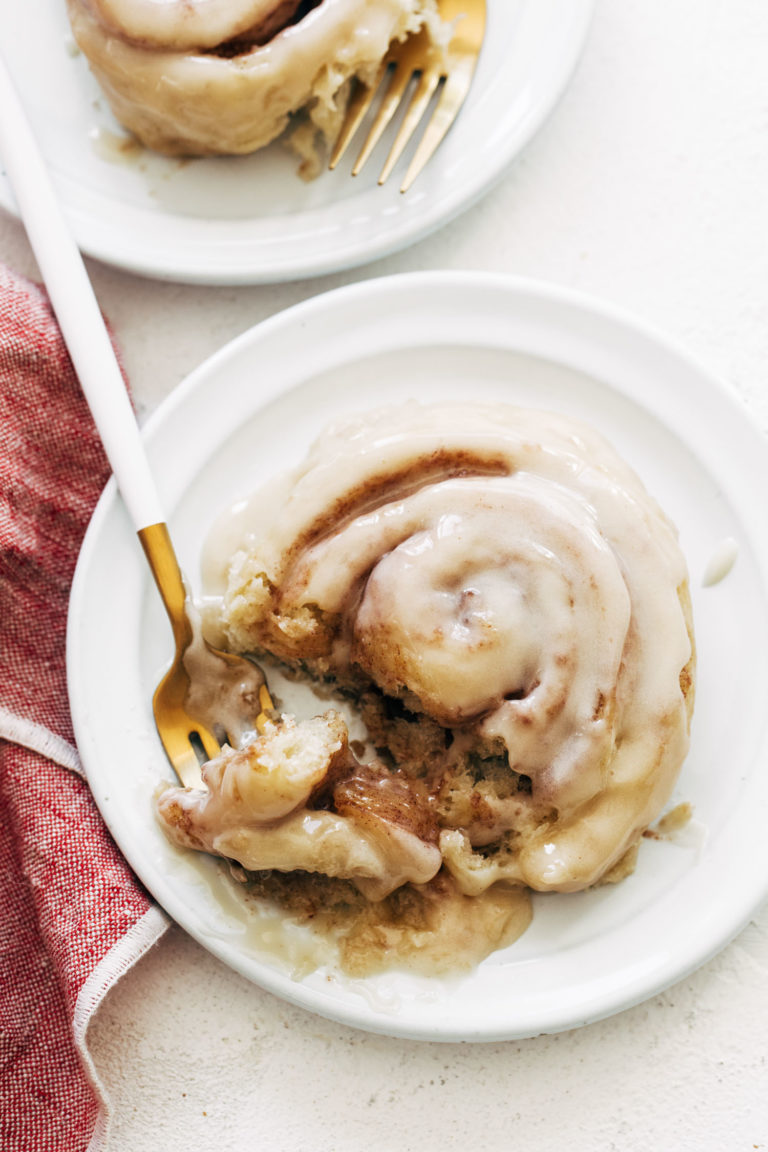 Cinnamon roll on a plate with a fork.