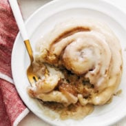 Cinnamon roll on plate with fork.