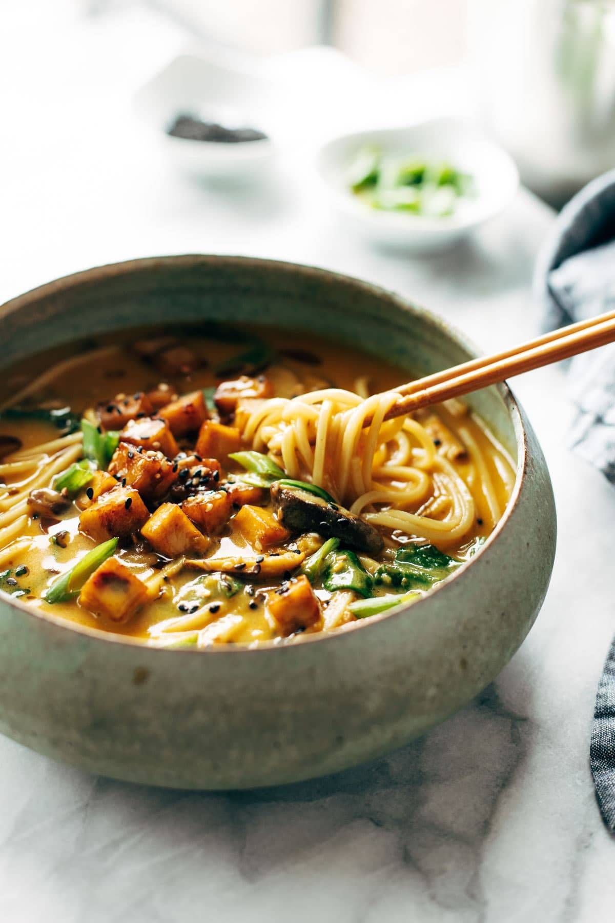 Coconut curry ramen in a bowl with noodle pull.