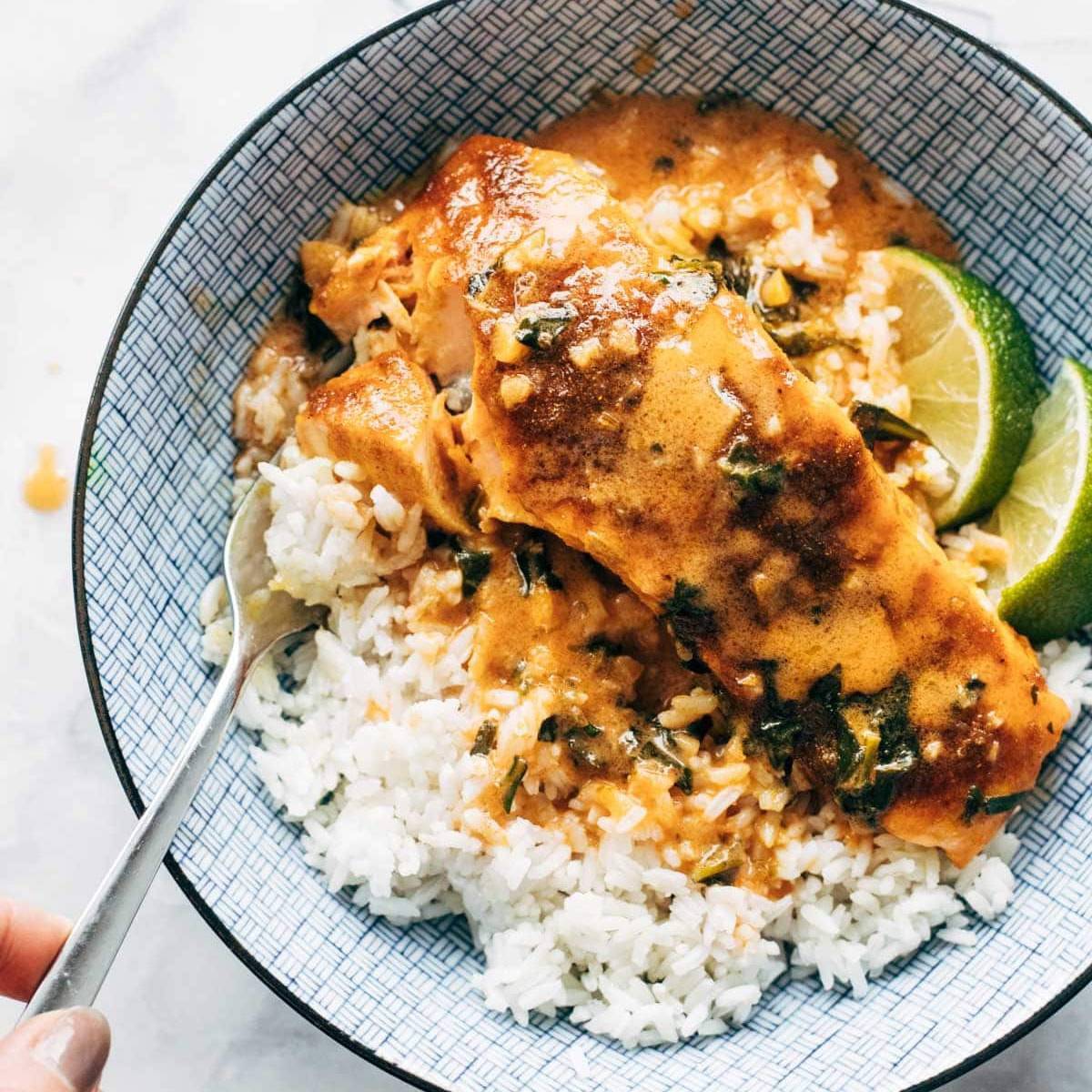 A meal of salmon, rice and curry sauce in a bowl.