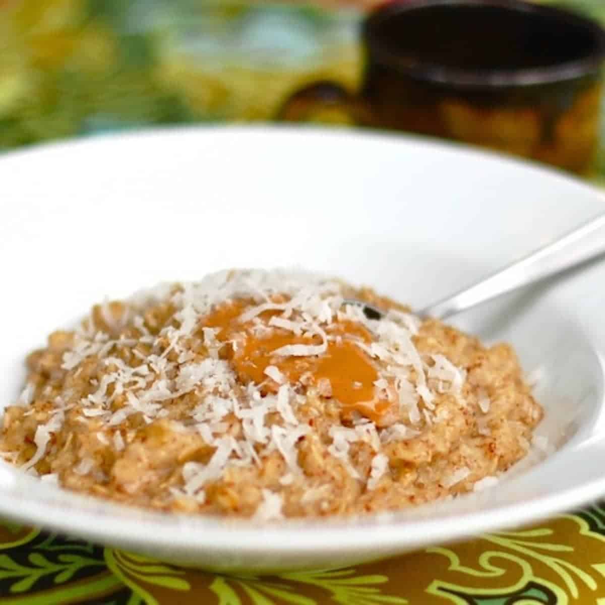 Coconut peanut butter oatmeal with coconut shreds in a bowl with a spoon.