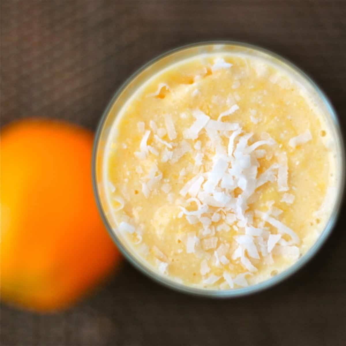 Coconut pineapple orange smoothie with coconut shreds on top.