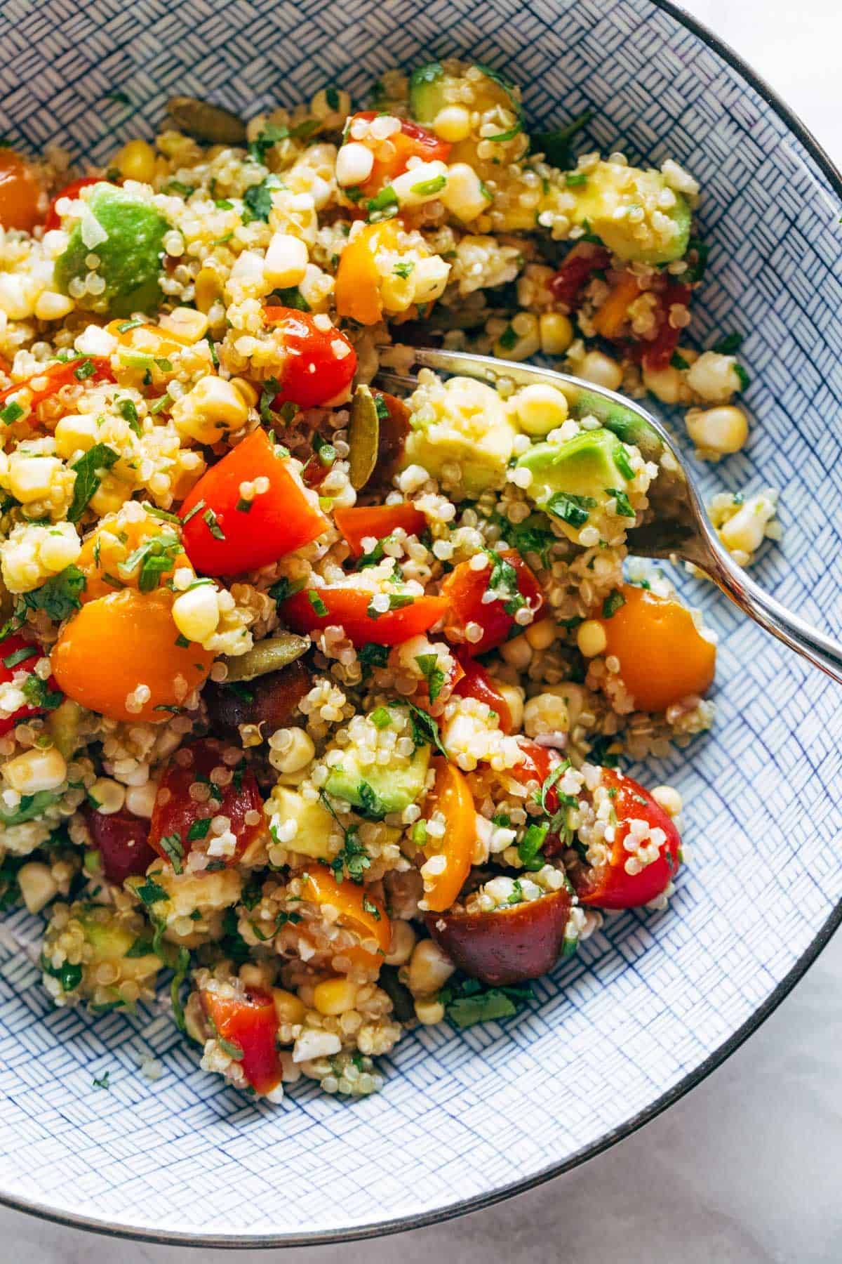 Corn, Avocado, and Quinoa Salad in a bowl with marinated tomatoes.
