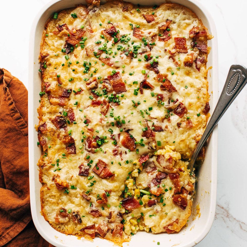 Corn casserole in a casserole dish with a spoon.