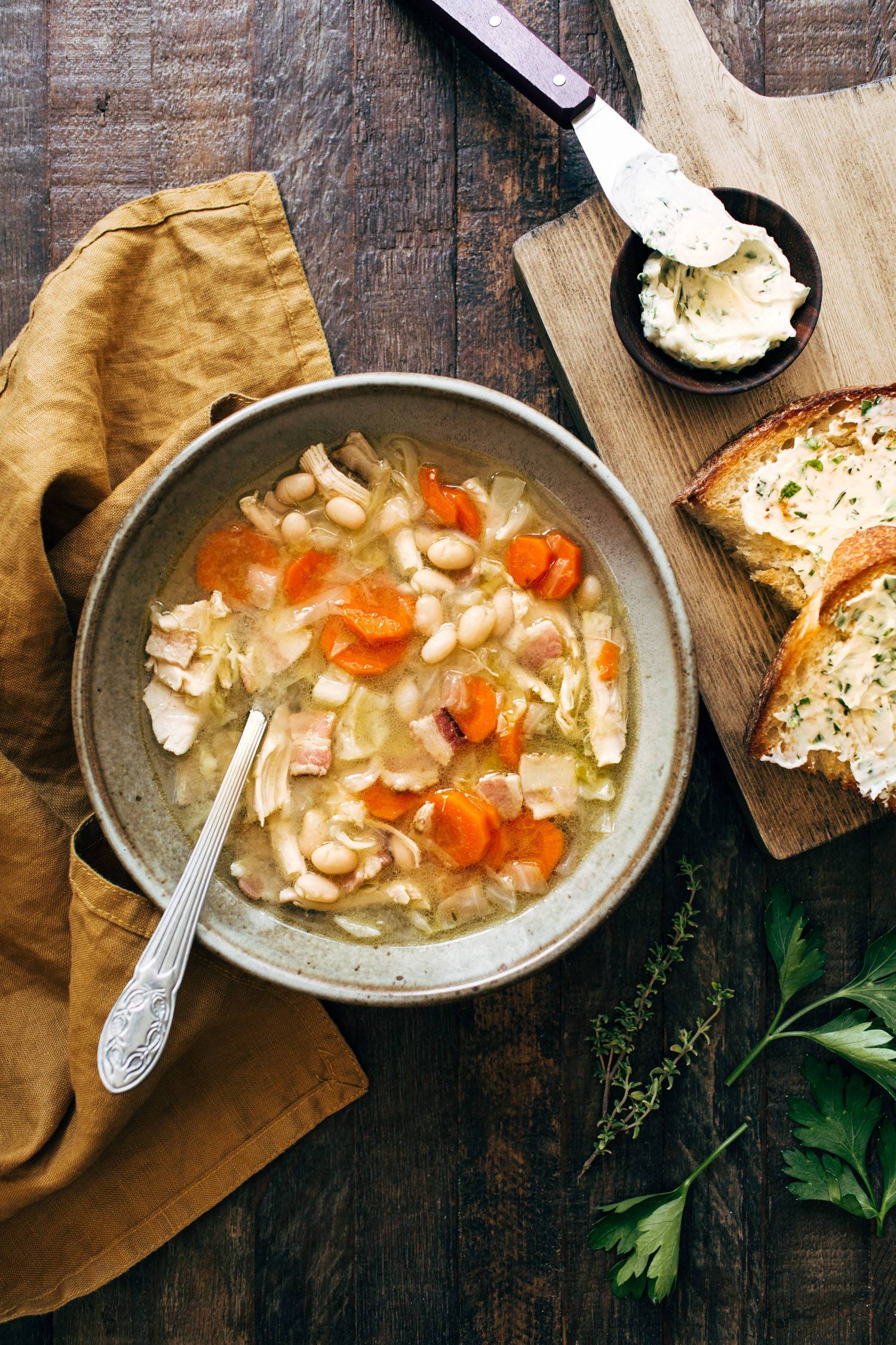 Chicken stew in a bowl with a spoon and bread on the side. 