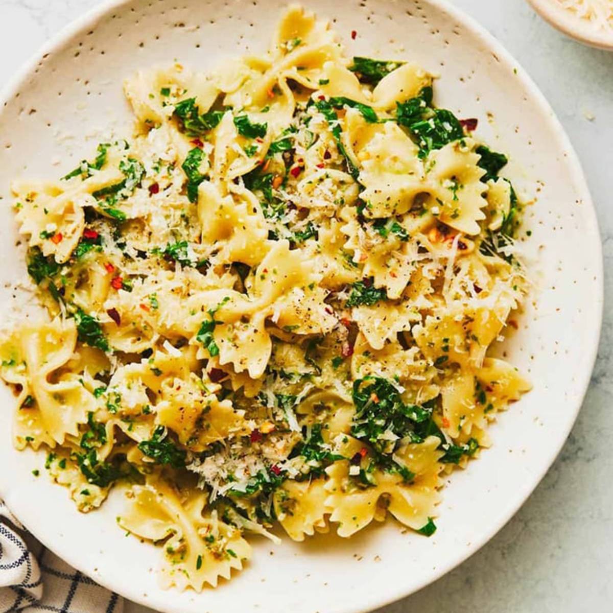 Bowtie pasta in a bowl with kale and cheese.