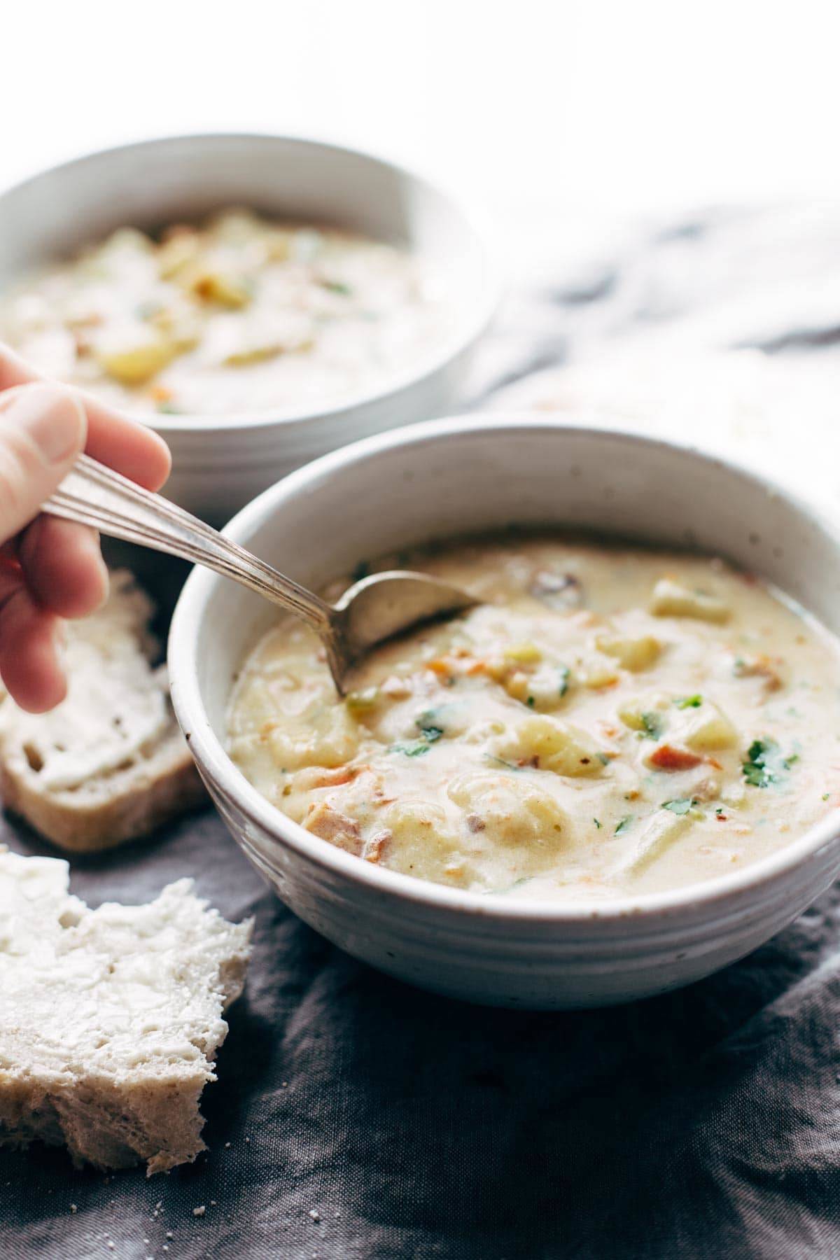Creamy Potato Soup in two bowls with a spoon and pieces of bread