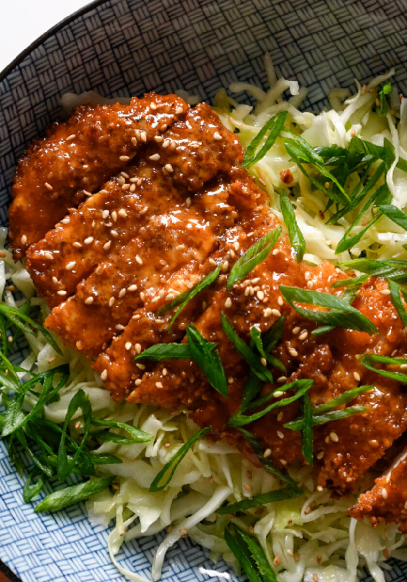 Gochujang chicken on a bowl of shredded cabbage.