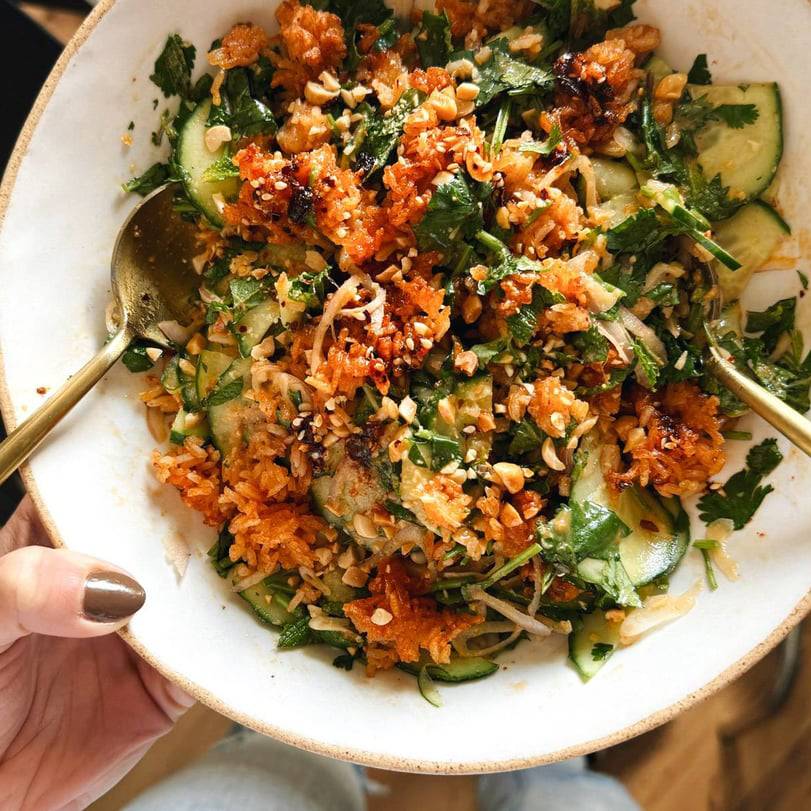 Crispy rice salad in a bowl with sliced cucumbers.