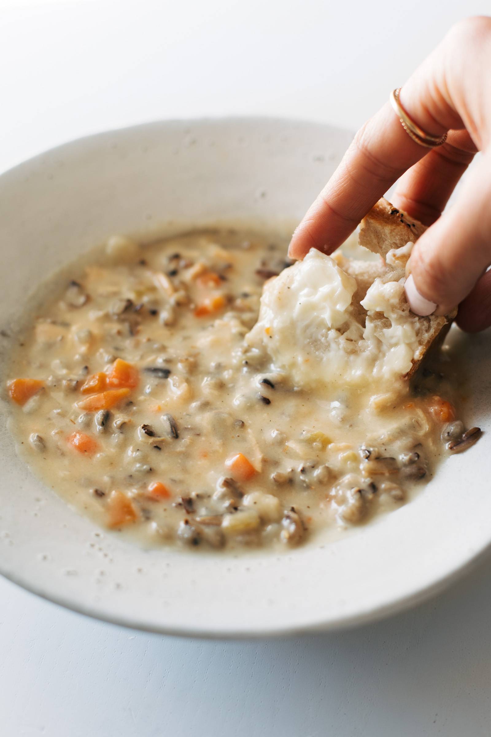 Dipping buttered bread into a bowl of wild rice soup.