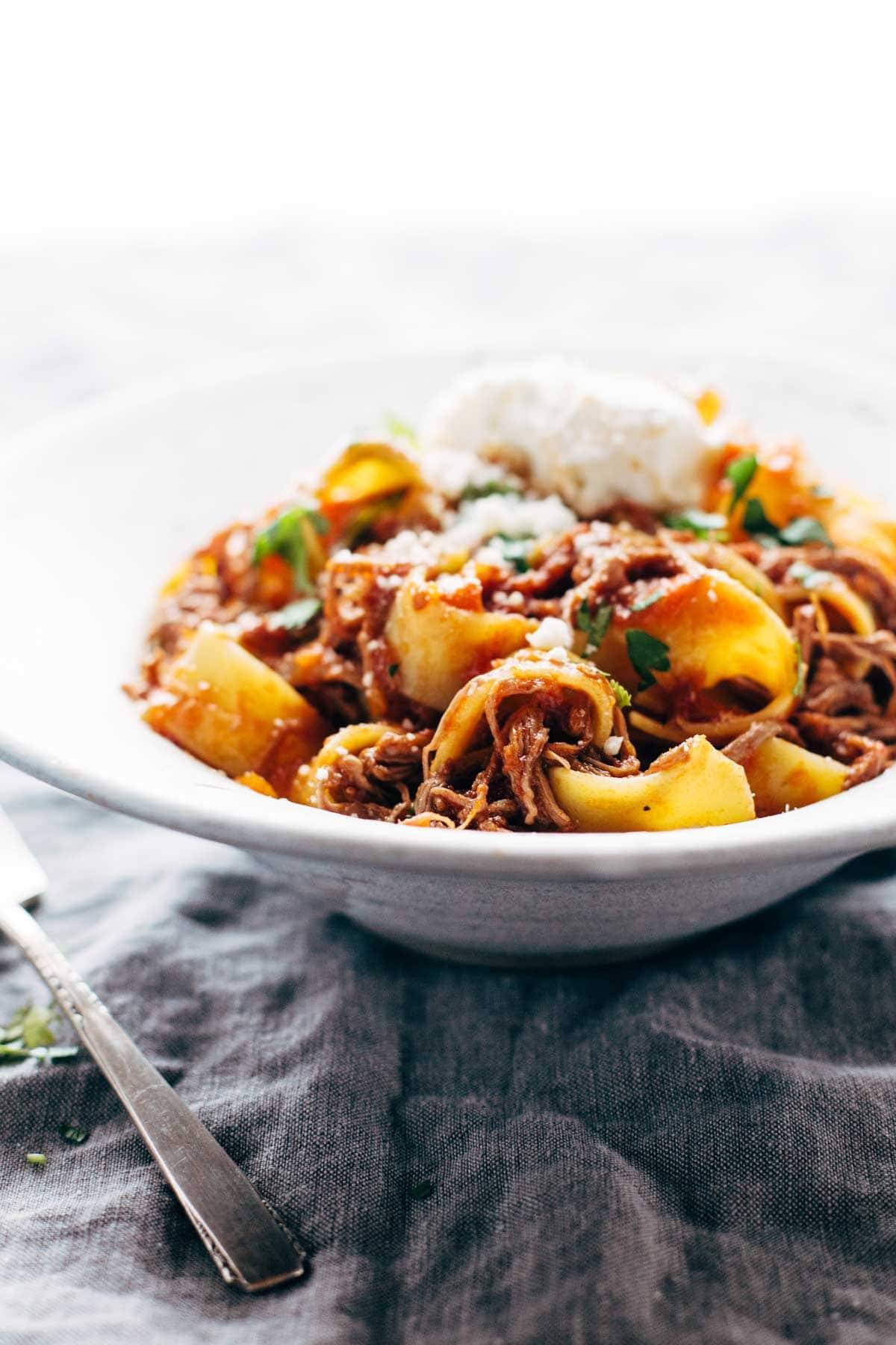 Beef ragu with pappardelle in a bowl with cheese. 