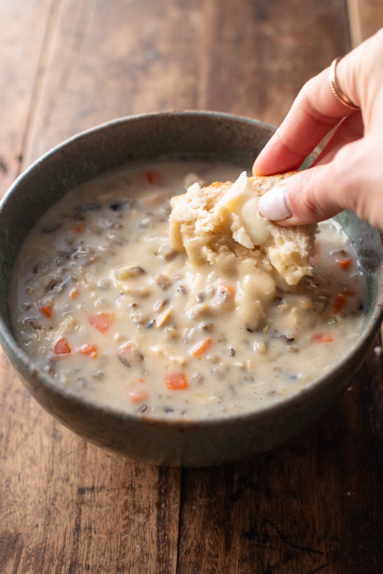 Dipping bread into a bowl of chicken wild rice soup.