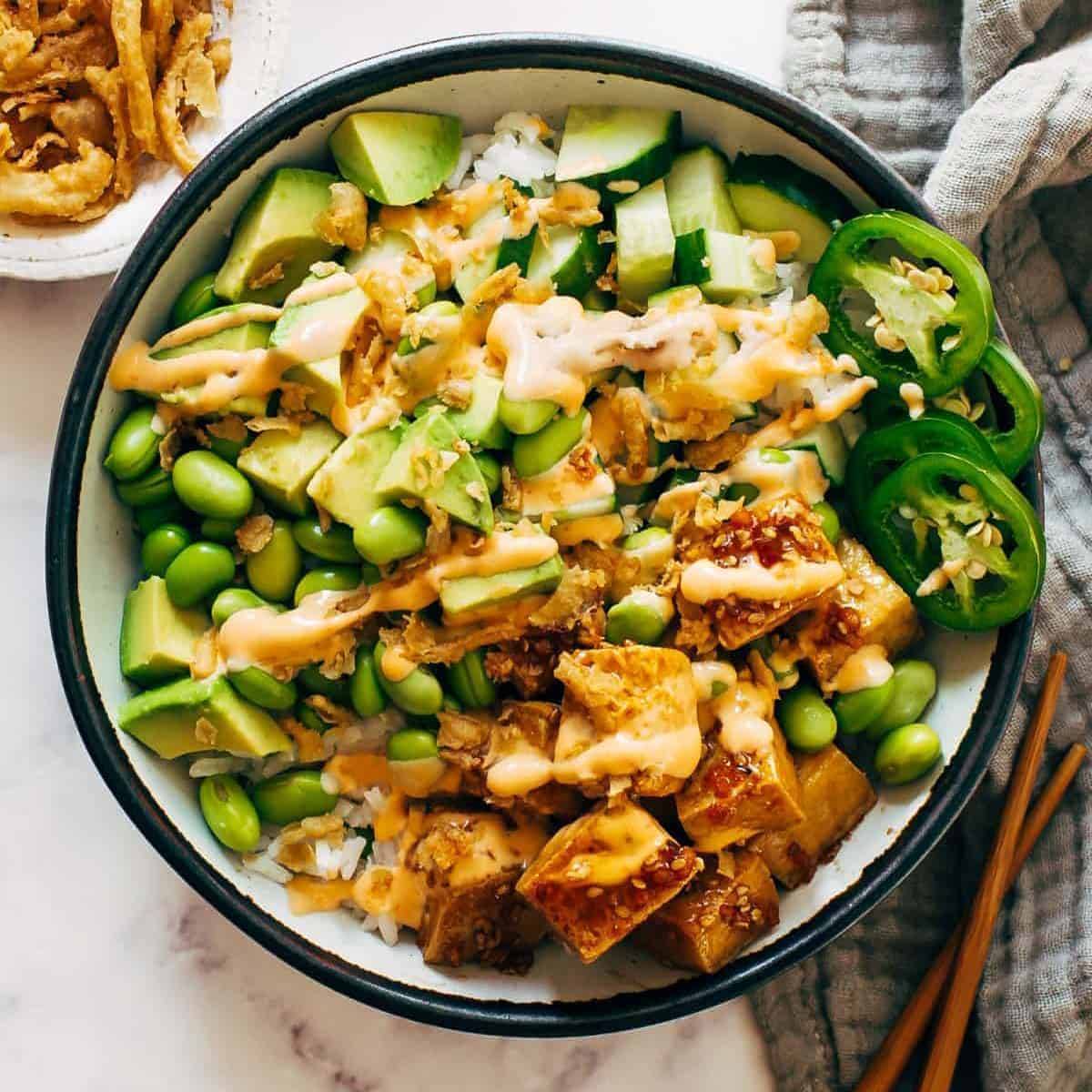 Crispy tofu with jalapeno peppers, cucumbers, and edamame in a bowl. 