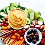 Curry Hummus on serving platter with vegetables and olives.