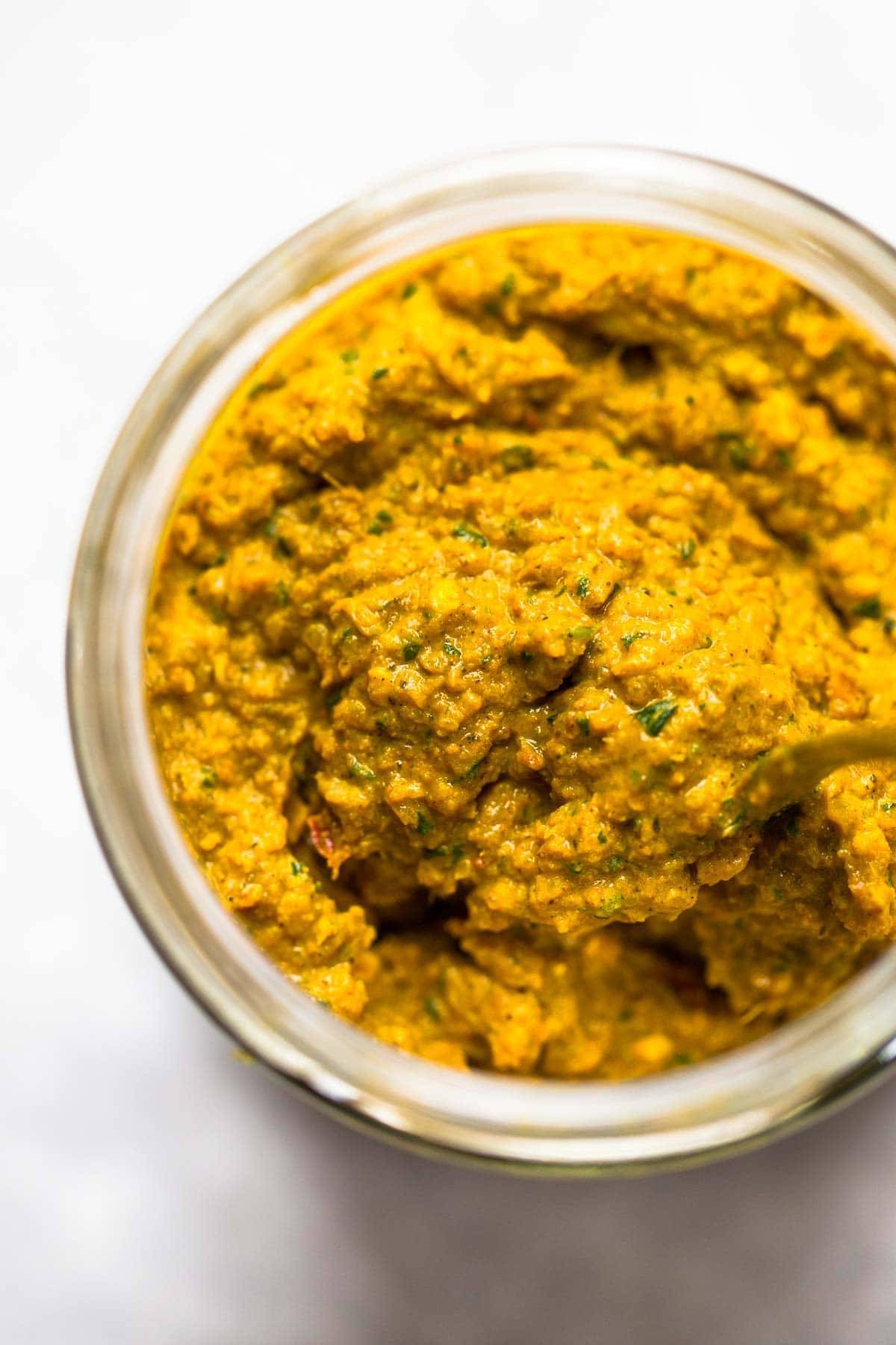 Homemade yellow curry paste in jar with spoon.