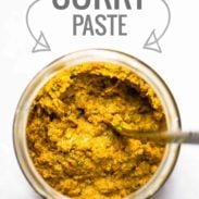 Homemade yellow curry paste in a jar with a spoon.