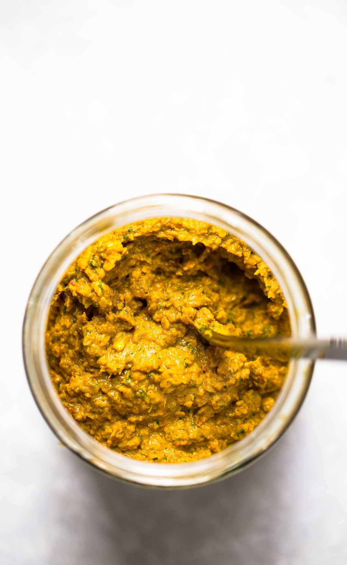 Yellow curry paste in a jar with a spoon.