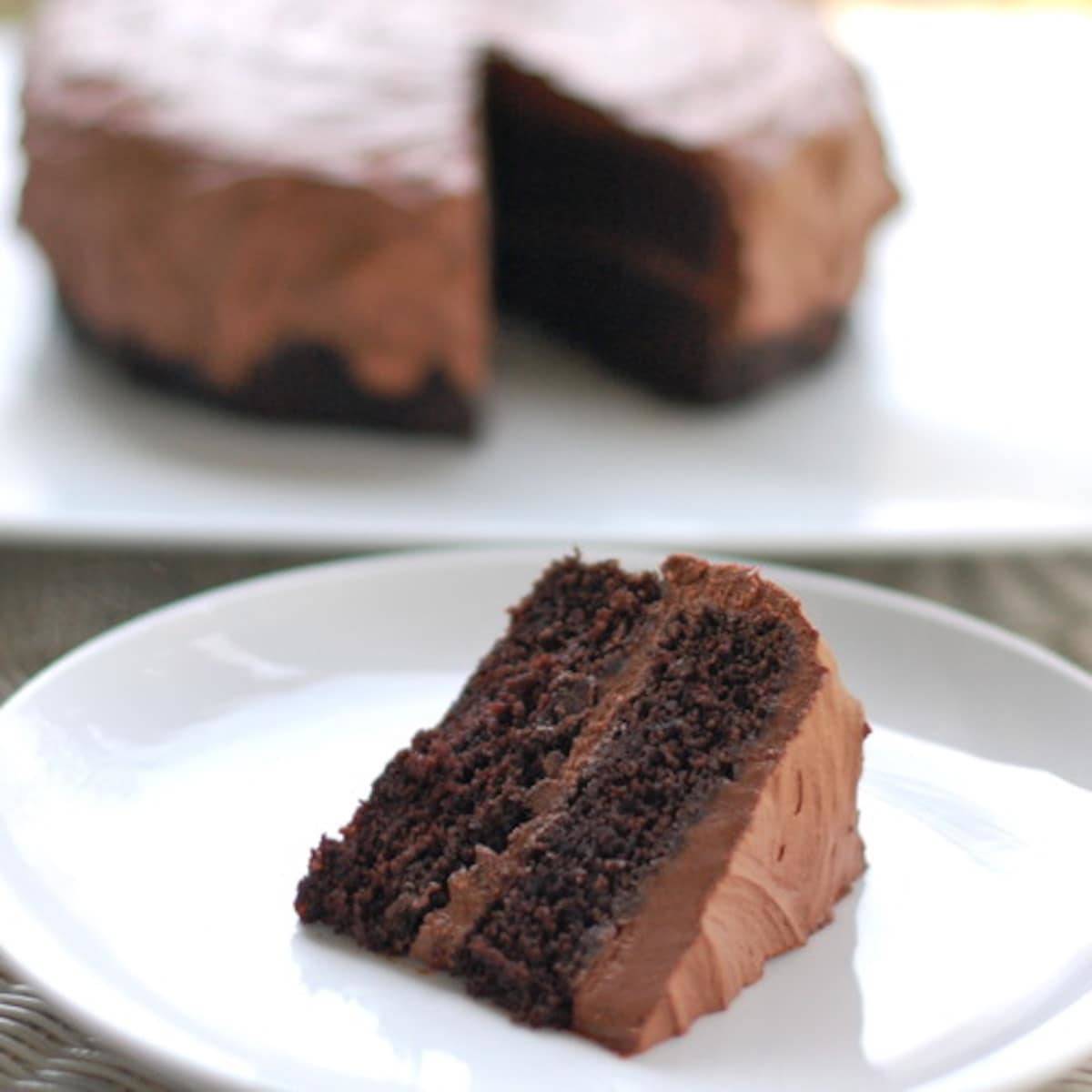 Slice of double chocolate cake with buttercream frosting on a white plate.