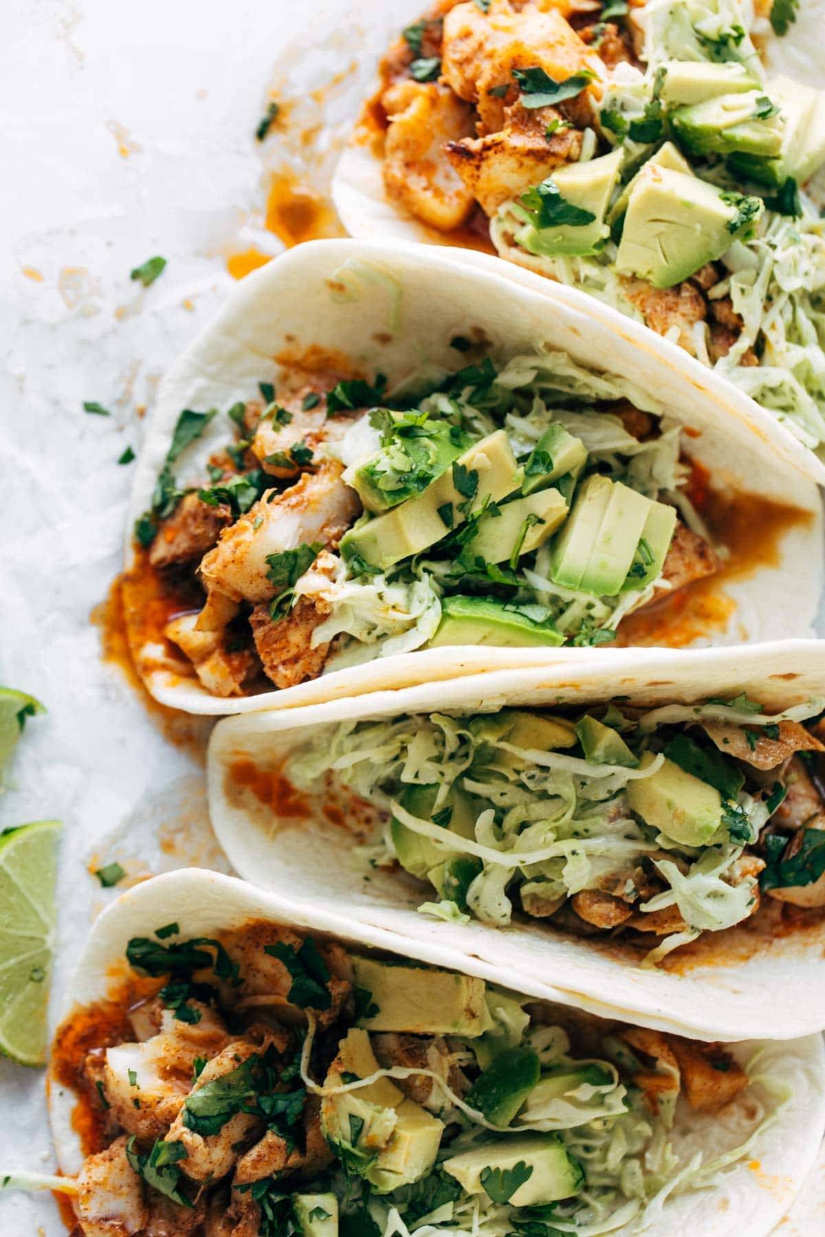 Fish tacos with sauce and diced avocados in them.