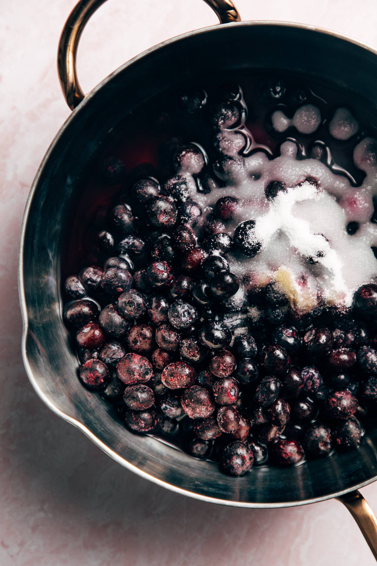 Homemade blueberry sauce in a pan with sugar