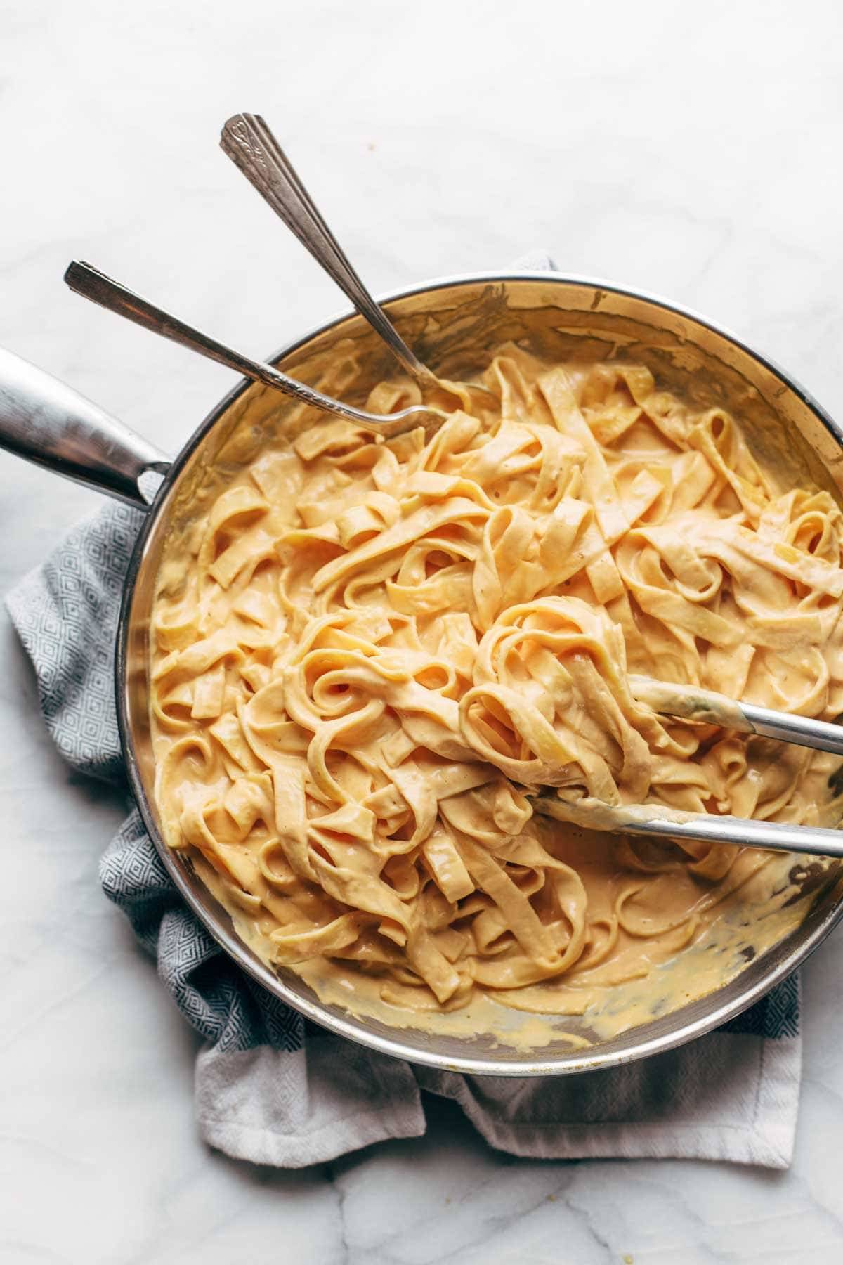 Pan filled with pumpkin alfredo and two spoons.