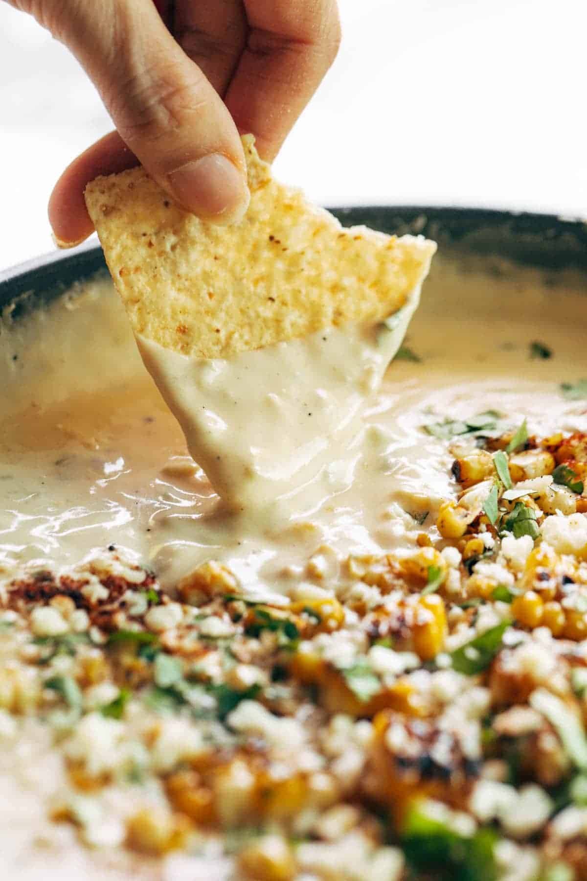 Chip dipping into elote queso.
