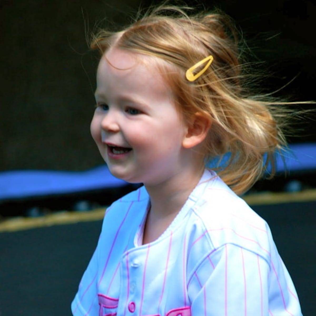 Little girl smiling with a yellow clip in her hair.