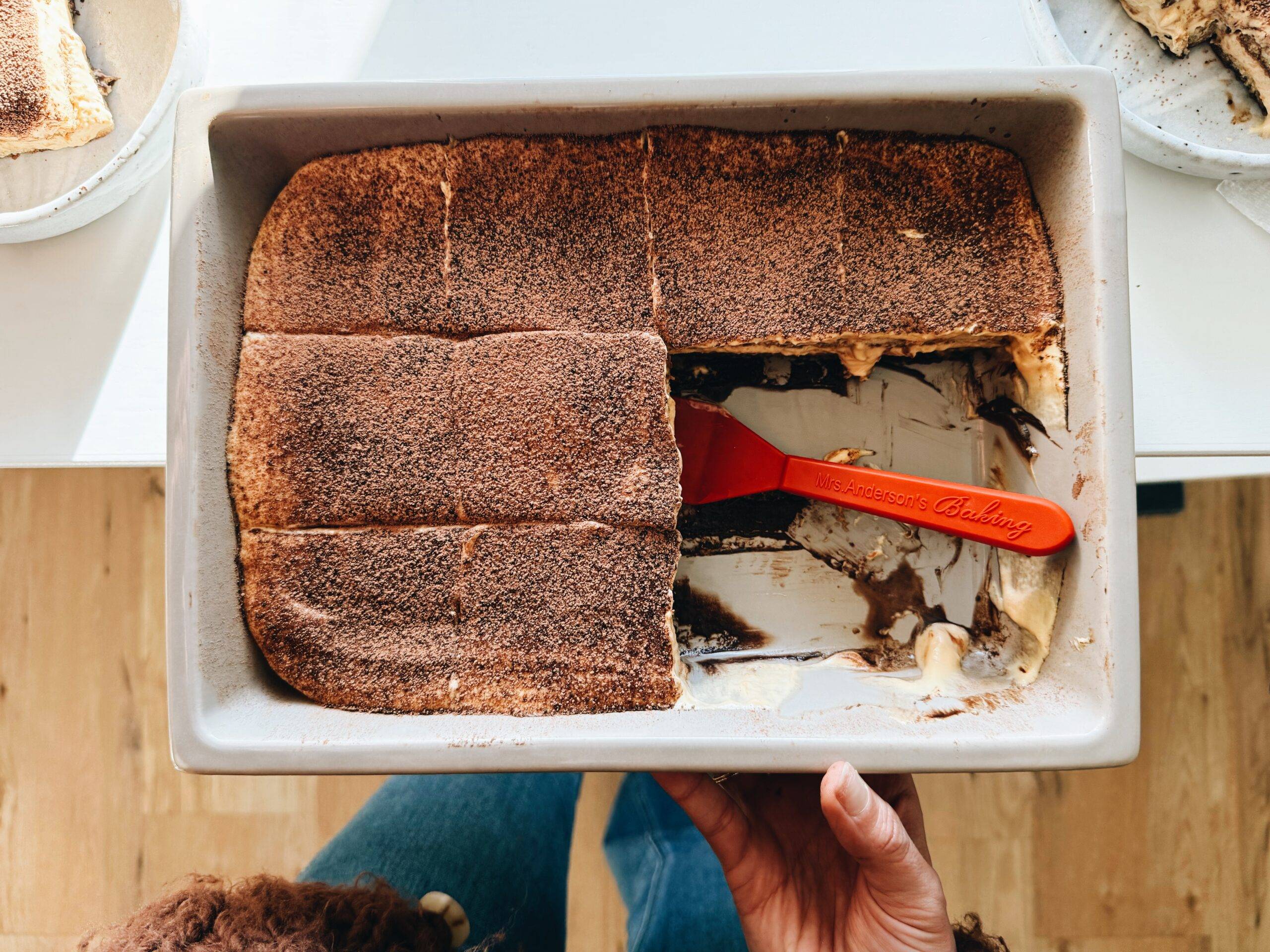 Slices of tiramisu in a pan with a spatula.