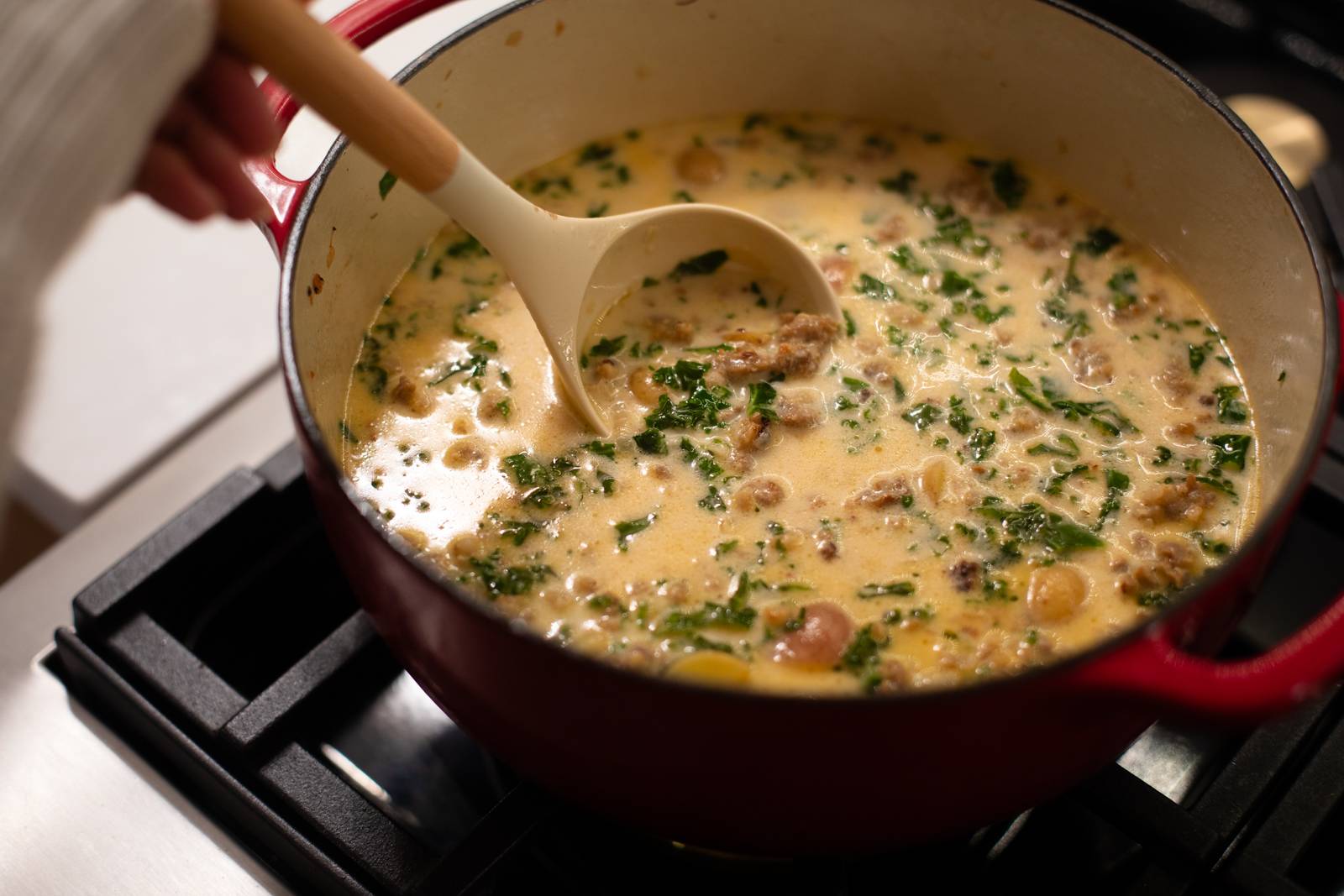 Ladling zuppa toscana out of a dutch oven.