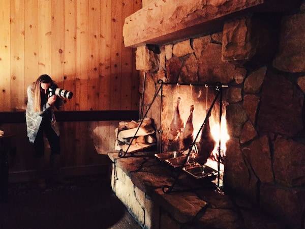 Woman taking a photo of a fireplace.
