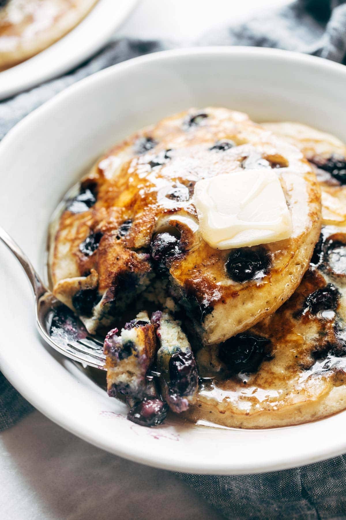 Blueberry pancakes on a plate with syrup and butter.