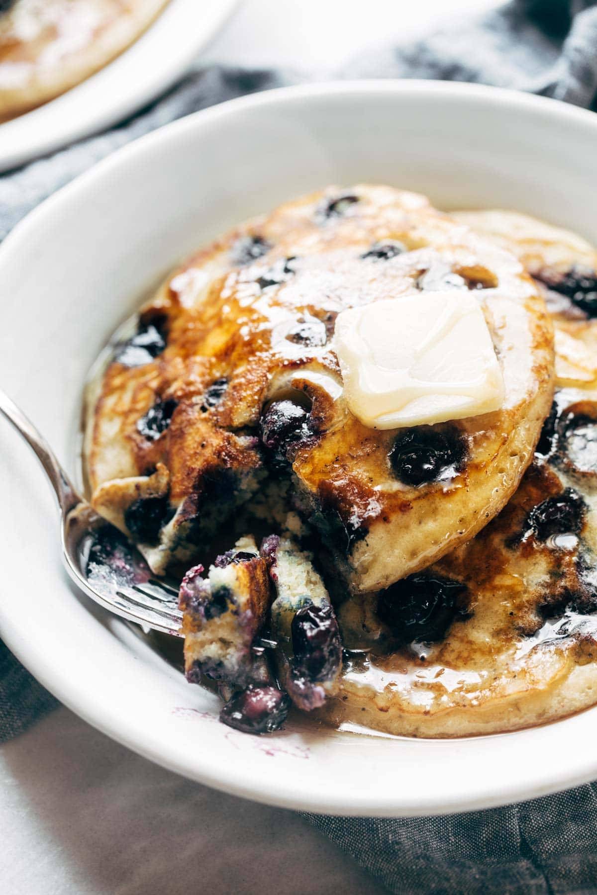 Blueberry pancakes on a plate with syrup and butter. 