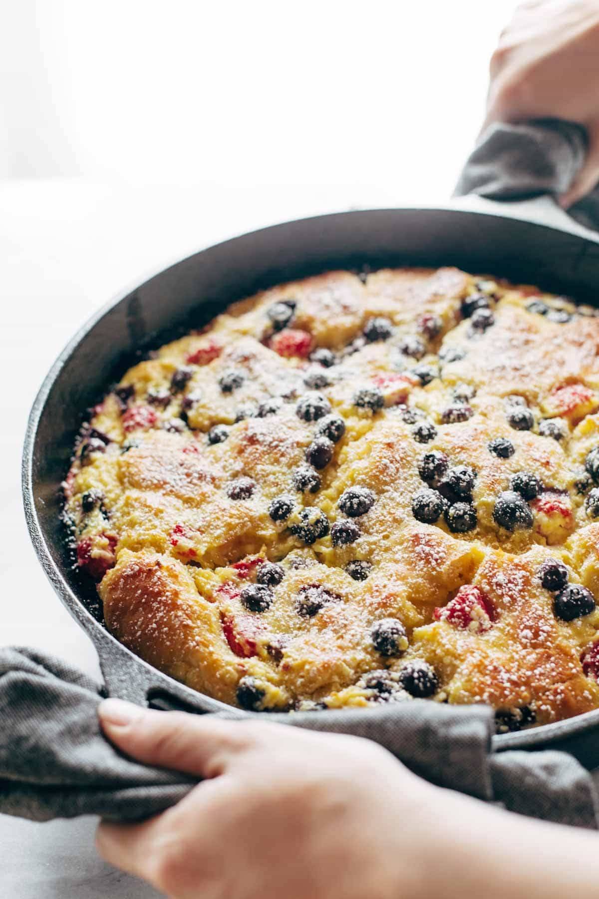 French toast casserole in a pan with two hands.
