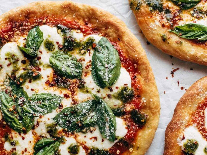 Fried Pizzas on parchment paper with basil.