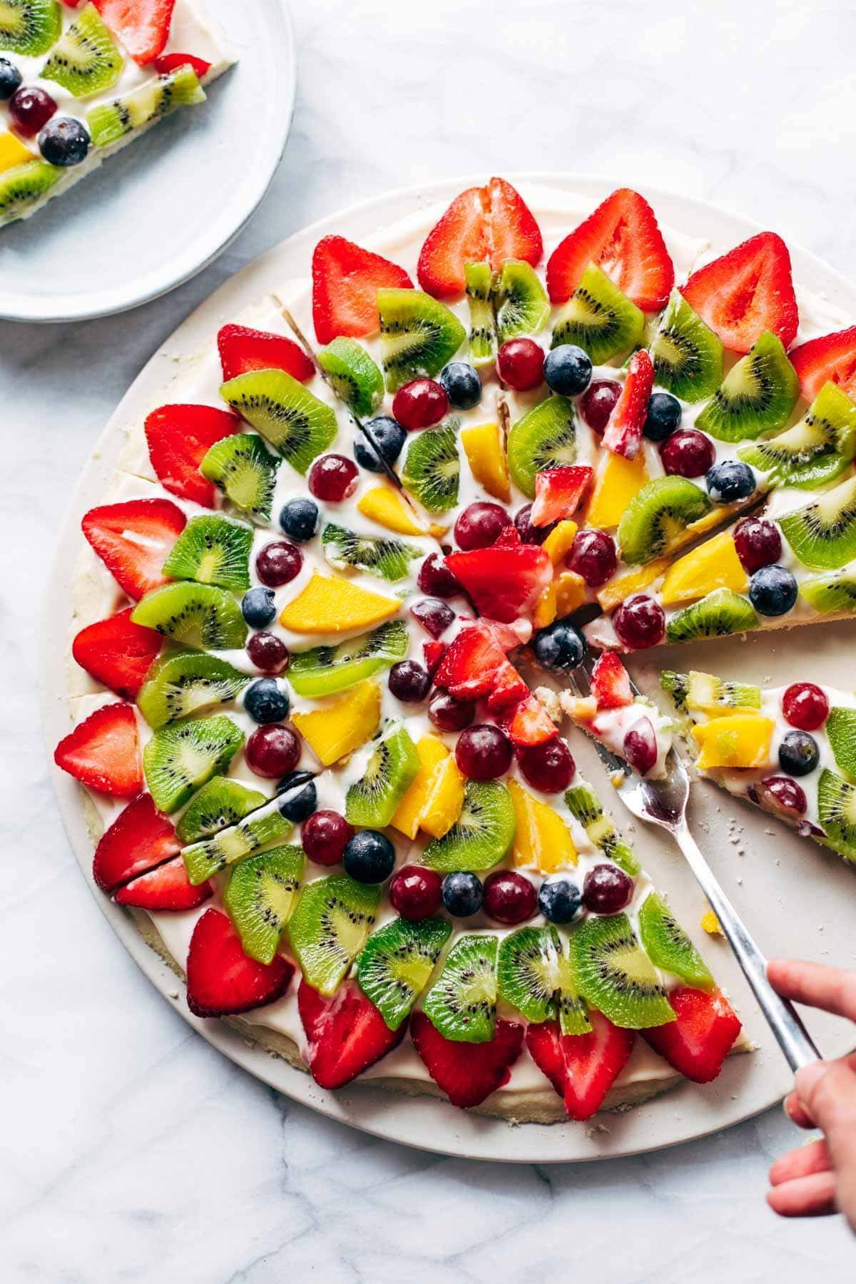 Taking a bite of fruit pizza with a fork. 