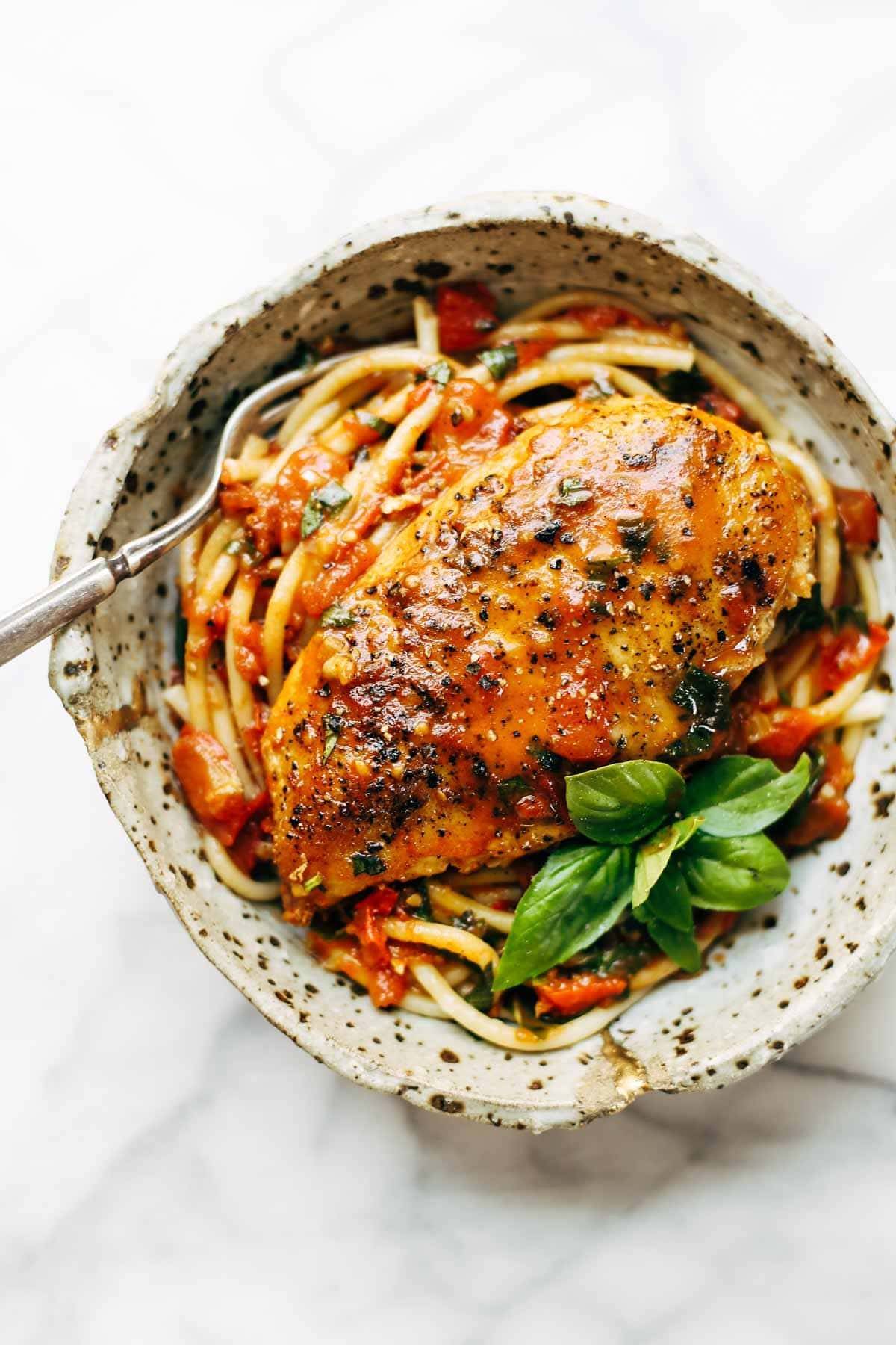 Garlic basic chicken, spaghetti and sauce in a bowl with a fork.