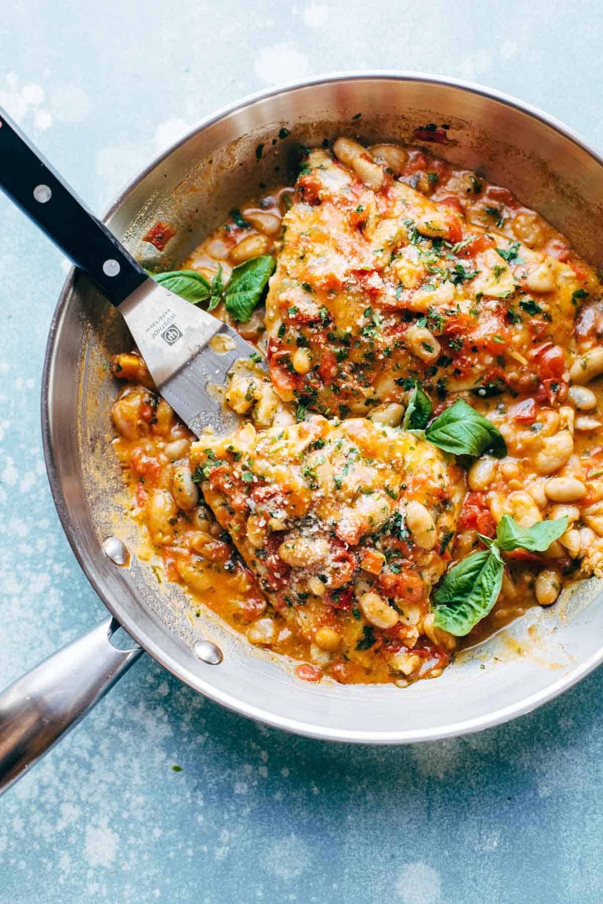 Garlic Basil Barramundi Skillet with Tomato Butter Sauce in a pan with a spatula.