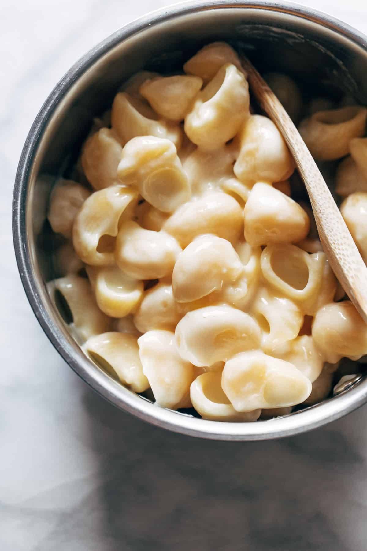 A bowl of shell pasta with wooden spoon.